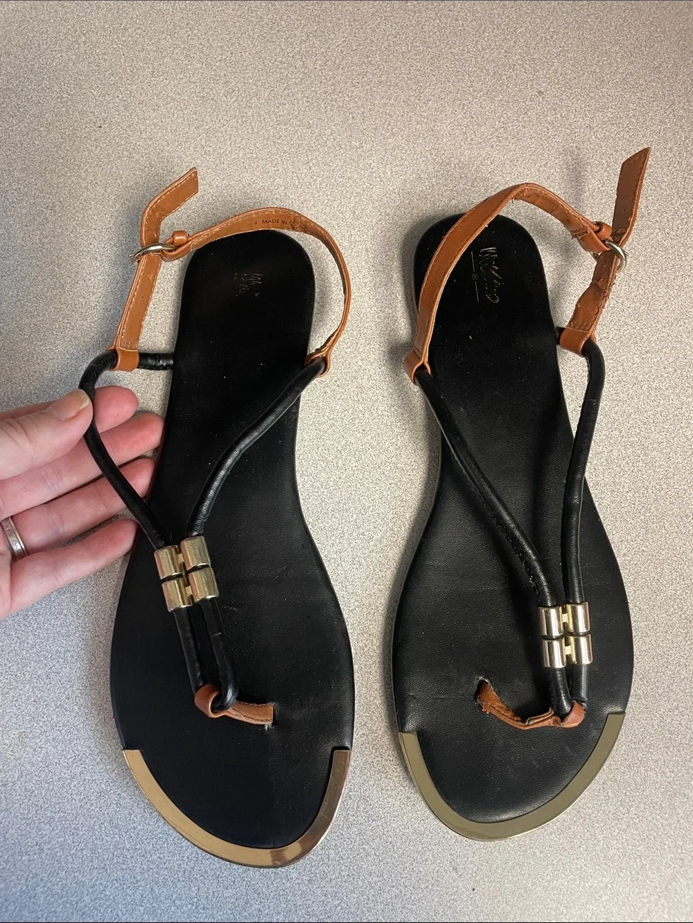 Black and brown t-strap sandals with gold accents